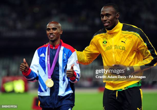 Great Britain Mo Farah with Usain Bolt after victory in the Men's 5000m final on day fifteen of the London Olympic Games in the Olympic Stadium,...