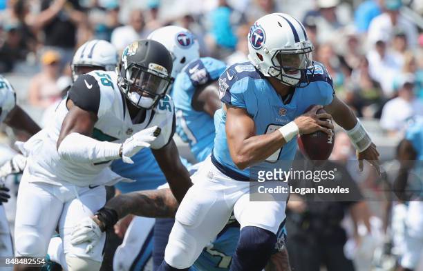 Marcus Mariota of the Tennessee Titans runs with the football in front of Dante Fowler of the Jacksonville Jaguars during the first half of their...