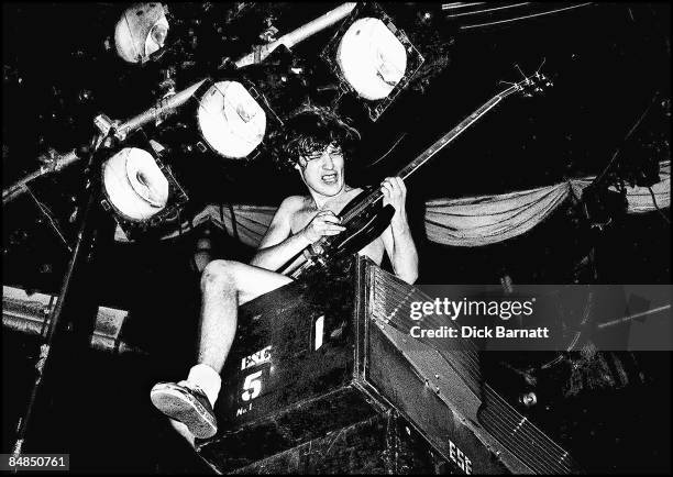 Photo of AC/DC; Angus Young performing live onstage on first UK tour, sitting on top of speakers