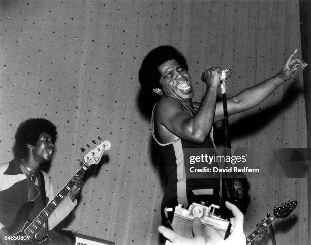 American soul singer and songwriter James Brown performs live on stage with the J.B.'s, including bass guitarist Bootsy Collins on left and guitarist...