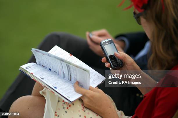 Female racegoer checks the form, and her Blackberry at Goodwood Racecourse