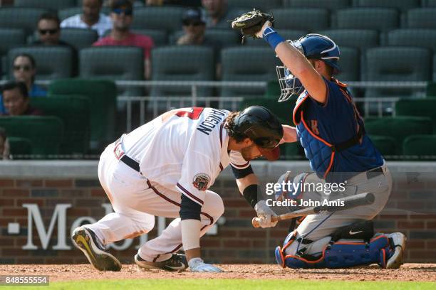 Dansby Swanson of the Atlanta Braves dives down to avoid a pitch as Kevin Plawecki of the New York Mets makes the catch in the ninth inning at...