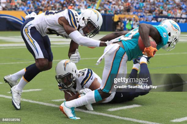 Jakeem Grant of the Miami Dolphins returns the punt and tries to get around Michael Davis of the Los Angeles Chargers and Charmeachealle Moore of the...