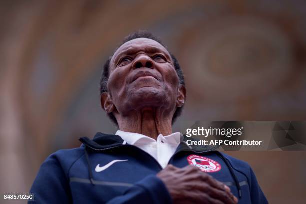 Olympic gold medalist Rafer Johnson listens to the National Anthem before pushing the ignition switch to light the Los Angeles Memorial Coliseum's...