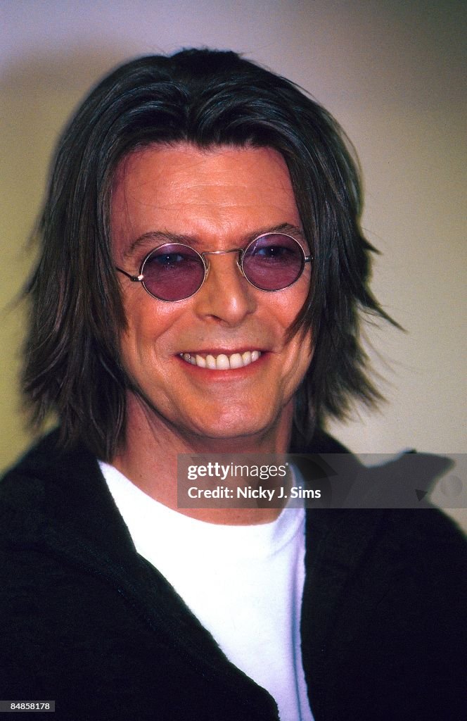 Photo of David BOWIE, posed, with long hair, wearing round