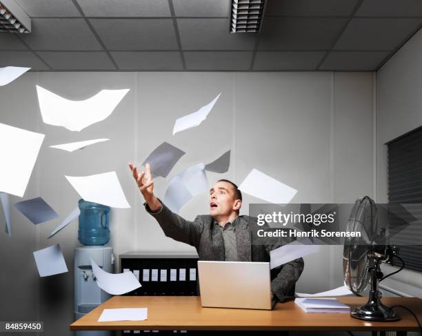 man trying to catch a bunch of flying papers. - air cooler stock pictures, royalty-free photos & images