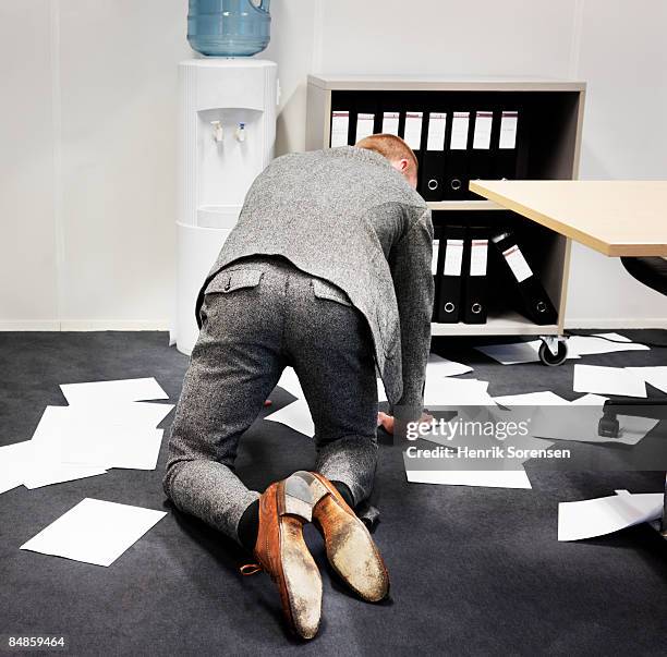 man picking up papers from the office floor. - knielen stockfoto's en -beelden