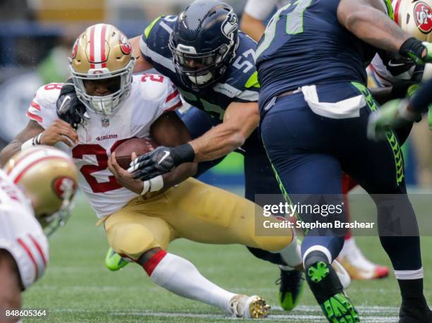 Running back Carlos Hyde of the San Francisco 49ers gains a yard before being tackled by linebacker Michael Wilhoite of the Seattle Seahawks during...