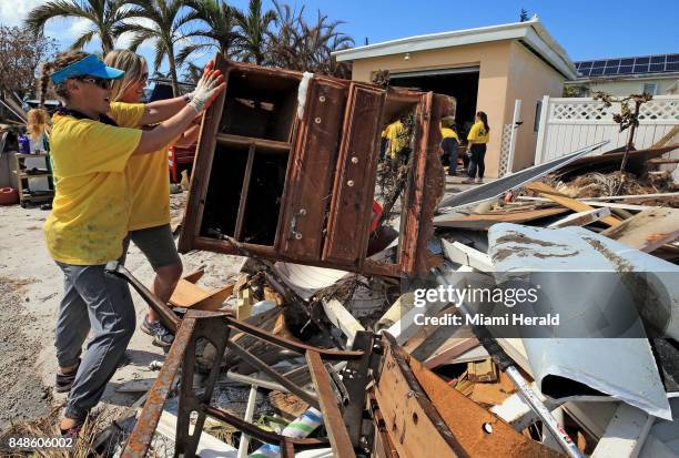 Maria Stotts and Heather Mueller, volunteers from the Church of Jesus Christ of Latter-Day Saints, clear debris from a Monroe County sheriff's deputy...