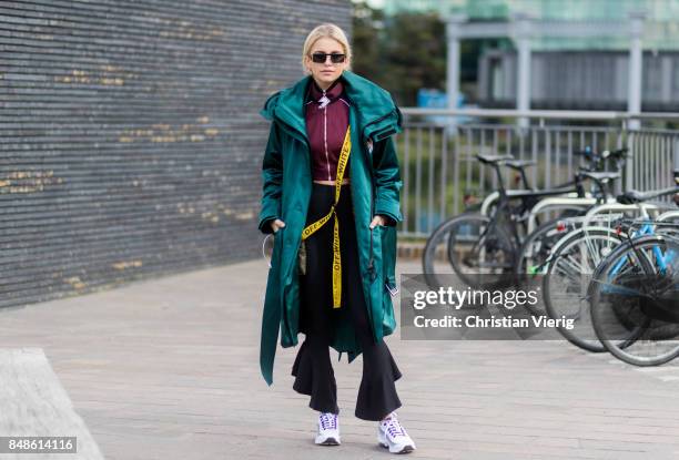 Caroline Daur wearing flared pants, green coat, cropped track suit jacket outside Versus Versace during London Fashion Week September 2017 on...