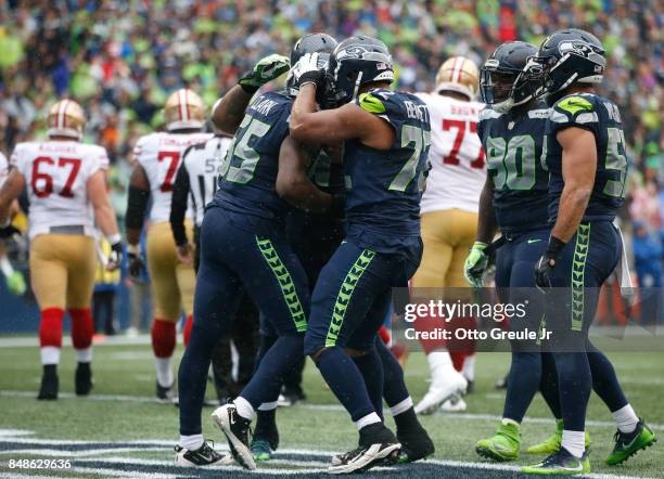 Defensive end Frank Clark of the Seattle Seahawks, left, celebrates sacking quarterback Brian Hoyer of the San Francisco 49ers with teammates,...