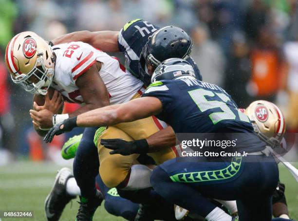 Running back Carlos Hyde of the San Francisco 49ers is taken down by middle linebacker Bobby Wagner of the Seattle Seahawks and linebacker Michael...