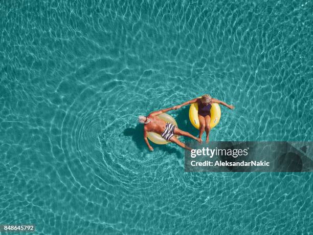 senior pareja disfruta de agua de mar - floating on water fotografías e imágenes de stock