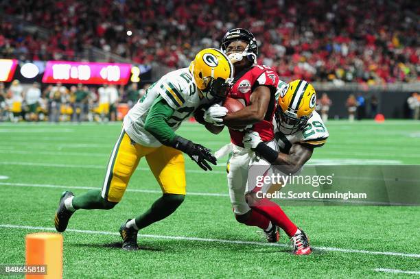 Damarious Randall and Kentrell Brice of the Green Bay Packers tackle Taylor Gabriel of the Atlanta Falcons during the first half at Mercedes-Benz...