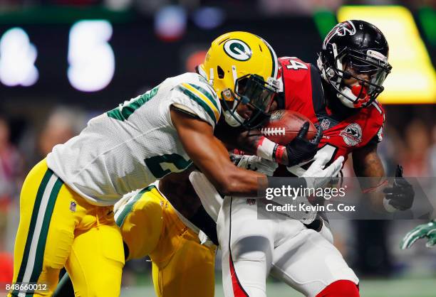 Davon House and Kevin King of the Green Bay Packers attempt to tackle Justin Hardy of the Atlanta Falcons during the first half at Mercedes-Benz...