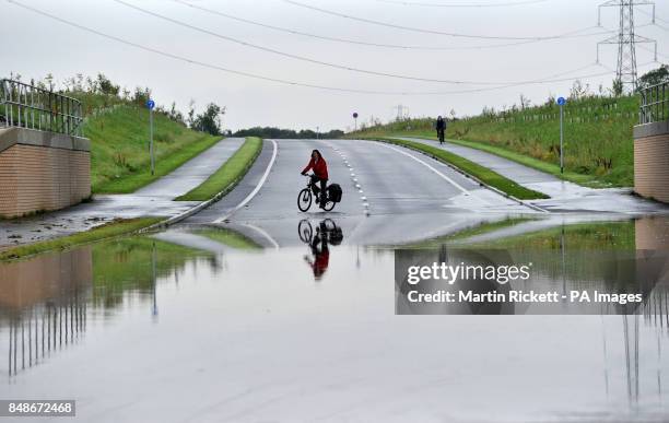 Cyclist avoids flood water on the closed A34 near Alderley Edge, Cheshire.