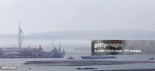 Royal Navy Type 45 Destroyer manoeuvres in the harbour as rain showers move towards Portsmouth and its landmark Spinnaker Tower as rain causes misery...