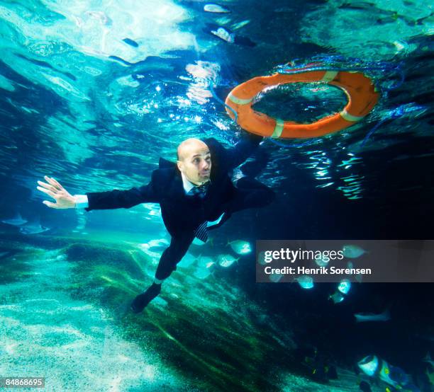 business man swiming under water holding on to a l - life belt stock pictures, royalty-free photos & images