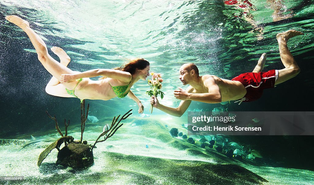 Man giving flowers to a woman under water