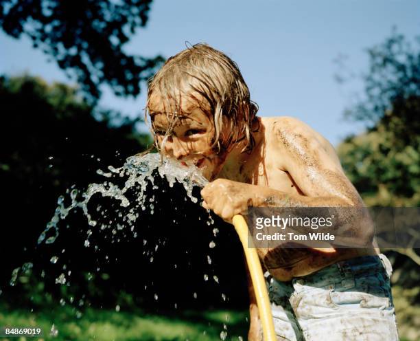 young boy drinking from a hose pipe - garden hose stock pictures, royalty-free photos & images