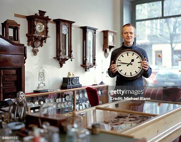 portrait of man standing holding clock in shop - antique stock pictures, royalty-free photos & images
