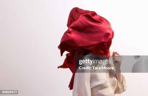 Woman with red silk blowing over face Woman with red silk blowing over face