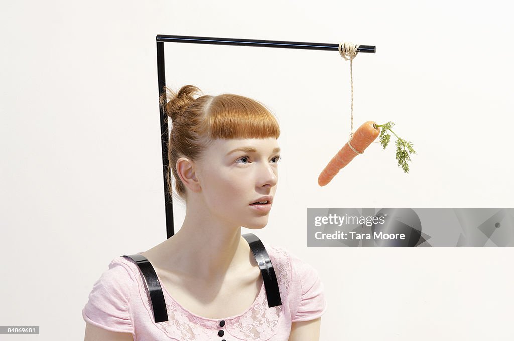 Woman with carrot dangling in front of face