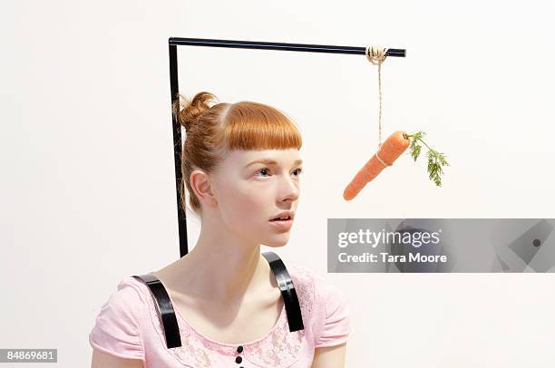 woman with carrot dangling in front of face - anreiz stock-fotos und bilder