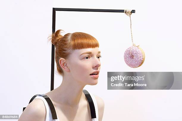 woman with donut dangling in front of face - desire stock-fotos und bilder