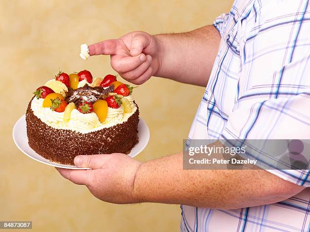 obese man holding fruit gâteaux with cream on - bulimia stock pictures, royalty-free photos & images