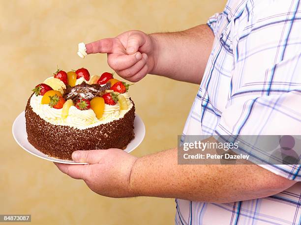 obese man holding fruit gâteaux with cream on - unhealthy living stock pictures, royalty-free photos & images