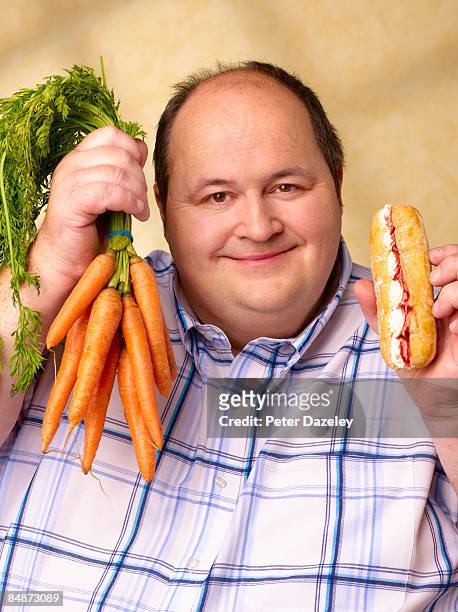 obese man with cream cake and carrots. - grasso nutrienti foto e immagini stock
