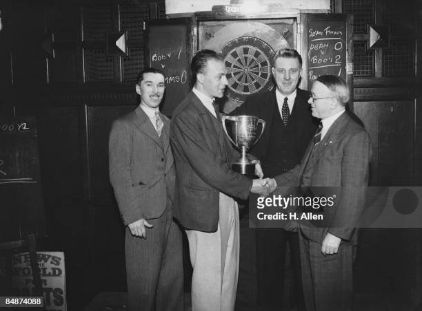 Booy receives the trophy from Aneurin Davies of the News Of The World, after winning the News Of The World Individual Darts Championship for the...