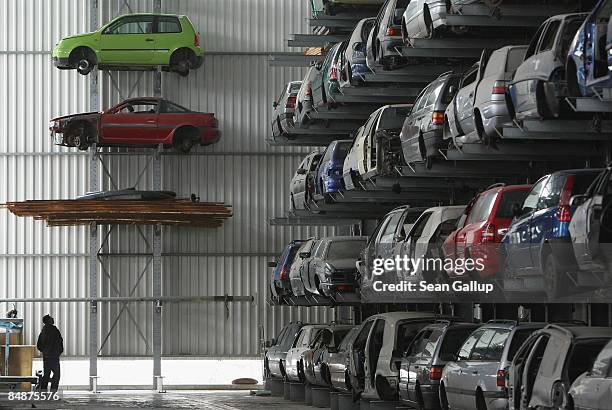 Man walks among wrecked and disused cars lying on shelves in a giant hangar at Berk car salvage on February 18, 2009 in Berlin, Germany. The German...