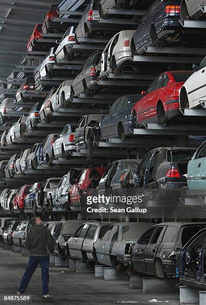Man walks among wrecked and disused cars lying on shelves in a giant hangar at Berk car salvage on February 18, 2009 in Berlin, Germany. The German...