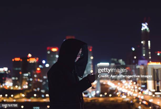 chinese man with smartphone standing on skyscraper roof - kapuze stock-fotos und bilder