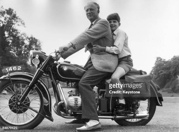 The Belgian royal family enjoy a day out at Laeken, a suburb of Brussels, 1953. The former King Leopold III straddles a motorcycle with his son,...
