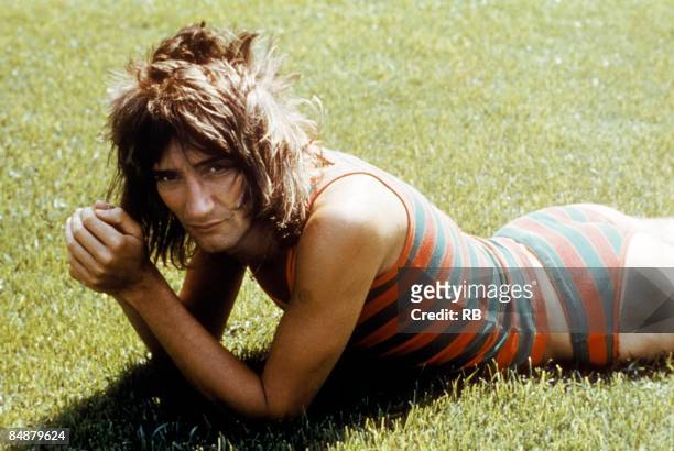 Photo of FACES and Rod STEWART; posed portrait of Rod Stewart lying on grass wearing striped bathing costume, Faces era