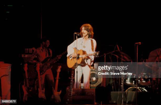 Photo of George HARRISON; performing live onstage on Dark Horse tour, playing acoustic guitar