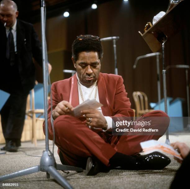 American trumpeter Dizzy Gillespie sits crossed legged writing notes during the recording of the BBC Television show 'Jazz at the Maltings' at Snape...