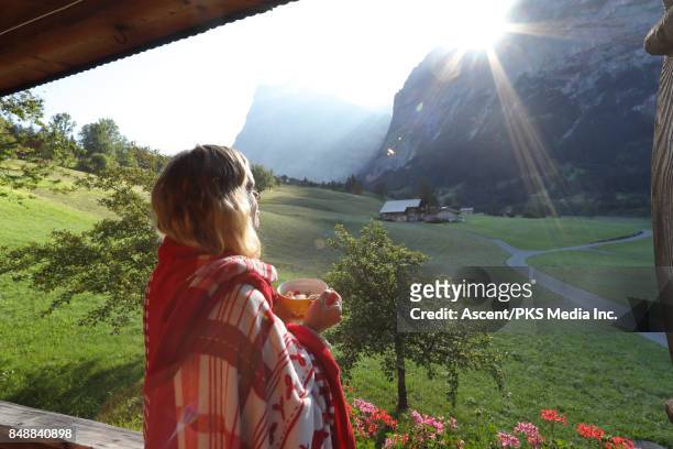 woman enjoys view from mountain chalet veranda - grindelwald switzerland stock pictures, royalty-free photos & images