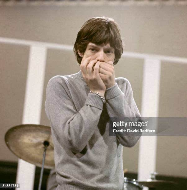 English singer Mick Jagger of rock group The Rolling Stones plays harmonica on the set of the ABC Television pop music television show Thank Your...