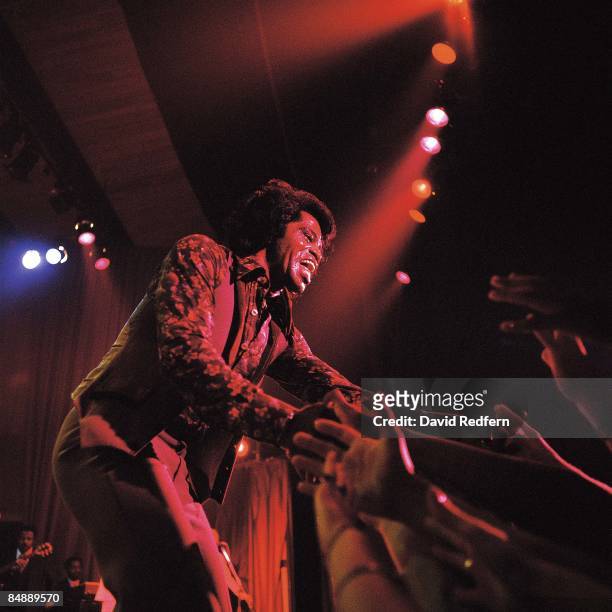 American soul singer and songwriter James Brown performs live on stage touching hands with members of the audience at The Venue in London in...