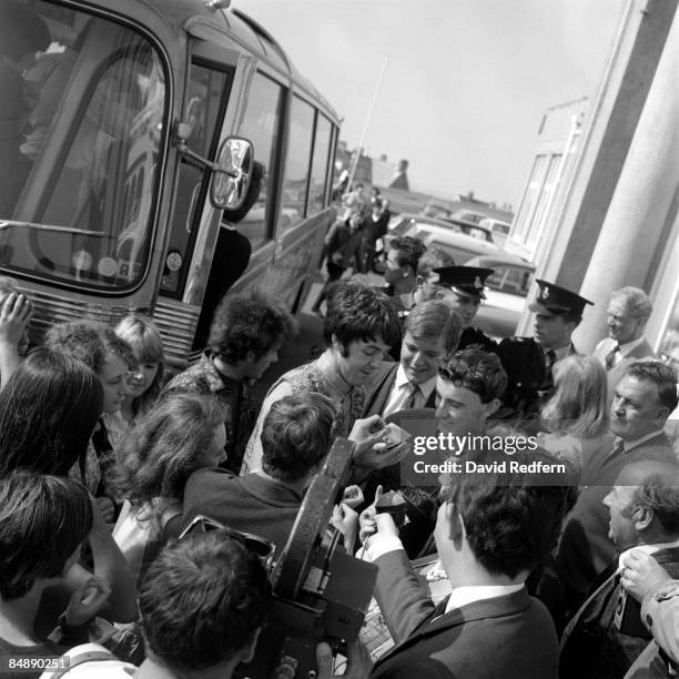 Paul McCartney of English rock and pop group The Beatles signs autographs for fans after emerging from the coach outside the Atlantic Hotel during...