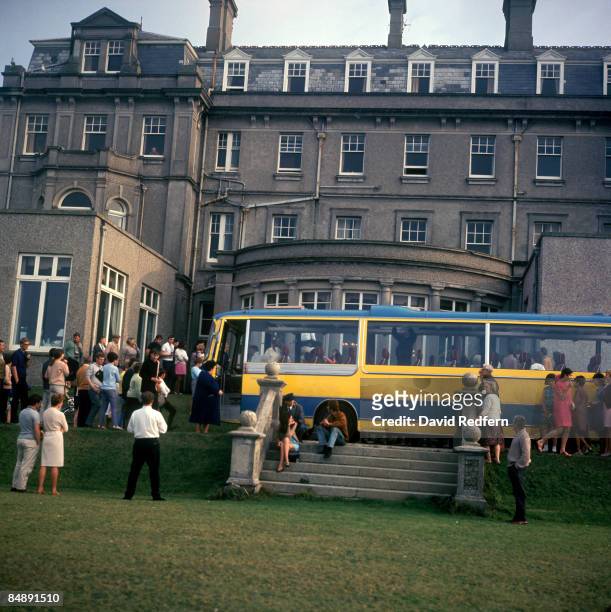 Local residents and film extras stand around the coach on the last day of location filming of the television musical film 'Magical Mystery Tour'...