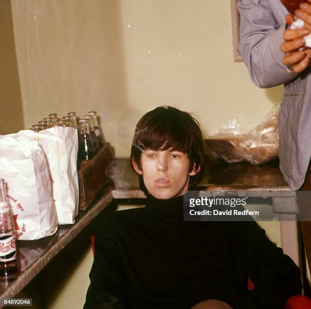 English guitarist Keith Richards of the Rolling Stones seated in a dressing room backstage at a venue in 1965.