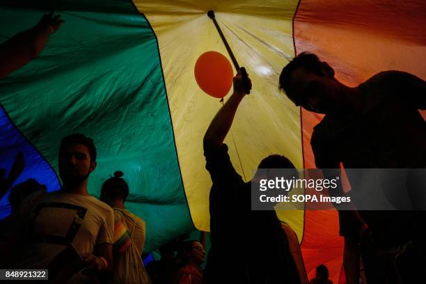 Participants are seen holding a large LGBT flag while walking through the street during the yearly Belgrade Gay Pride. Gay Pride in Serbia has been...