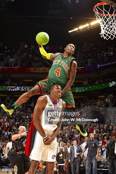 Slam Dunk Contest: New York Knicks Nate Robinson in action, leaping over Orlando Magic Dwight Howard during finals on All-Star Saturday Night of All...