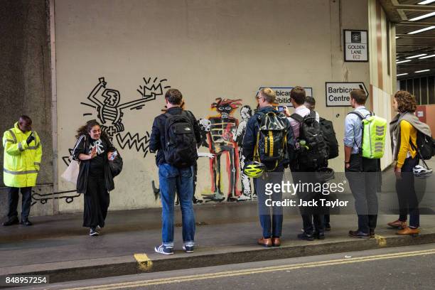Woman is reprimanded by a security guard for touching a new work by street artist Banksy on a wall by the Barbican Centre as members of the public...
