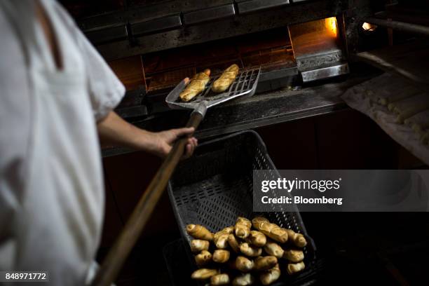 Worker takes canillas, banquette-like bread popular in the country for decades, out of an oven at a bakery in Caracas, Venezuela, on Wednesday, Aug....